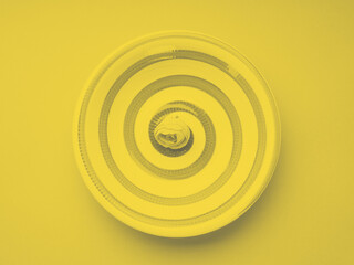 Illuminating yellow and gray toned ceramic dish with hypnotizing spiral. Top view, color of the year