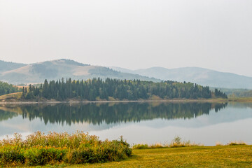 Reflections in the lake on a hazy morning. Chain Lakes Provincial Park, Alberta, Canada