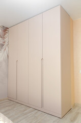 Beautiful light wardrobe in the bedroom. Modern furniture. Vertical photo