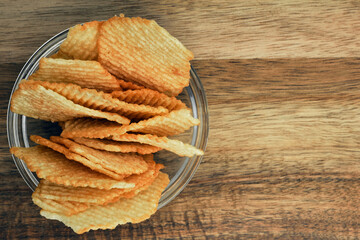 Corrugated potato chips on a wooden board. Snack, junk food. Close up.