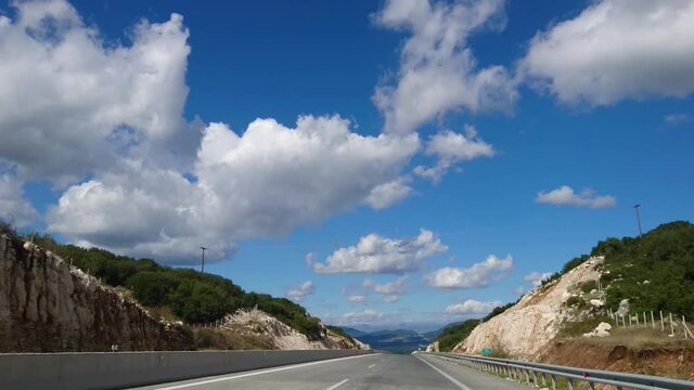 Driving highway mountain road in Greece on a sunny summer day with scenic cloudscape view