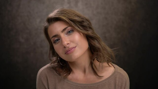 Cute woman looks dreamily turns toward camera flirts with eyes smile