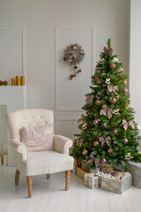 Classical interior of a white room with a Christmas tree, garlands, candles, lanterns, gifts and white armchair.