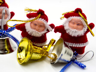 three funny santa claus toys with christmas bells on white background. In focus and out of focus