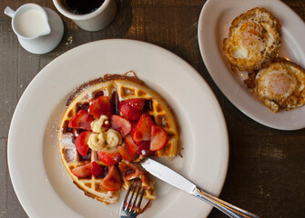 Buttermilk waffles with butter, maple syrup and crispy southern fried chicken. Classic American breakfast or brunch favorite. Made from scratch  waffles served with butter and maple syrup.