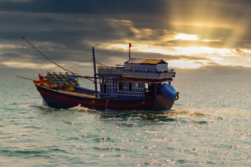 Vietnamese fishing boat for fish and squid. Open sea. Open water at bright sunset