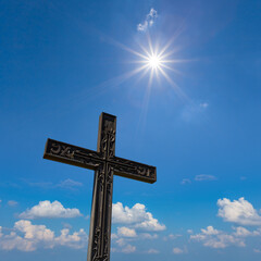 closeup christian cross uplift on the cloudy sky with sparkle sun background