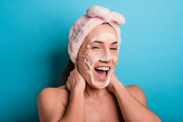 Beautiful happy young woman with cosmetic foam in her face wearing a pink turban after having a...