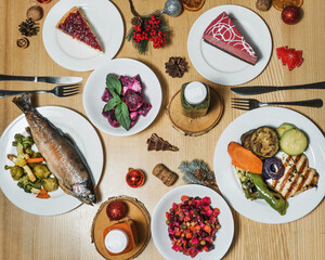 New Year's dinner for two. On the table are steamed fish and vegetable dishes, chicken breast and grilled vegetables. Beetroot salads. Festive desserts and smoothies. Christmas decor on the table.