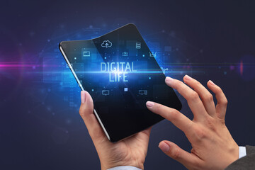 Businessman holding a foldable smartphone with DIGITAL LIFE inscription, cyber security concept