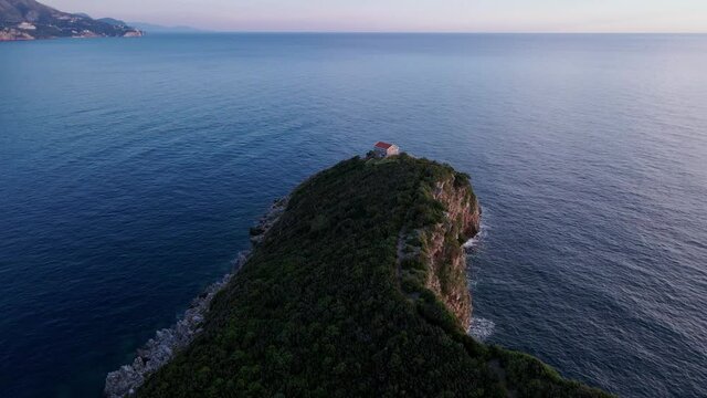 Camera zooms in on lonely fishing lodge on mountain ledge in sea. Secluded wine-growing area on top of cliff with vineyards on slope. Beautiful seascap from bird eye view.