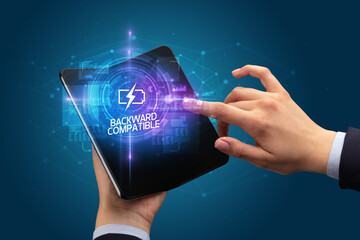 Businessman holding a foldable smartphone with COMPUTING inscription, new technology concept BACKWARD COMPATIBLE