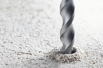 metal drill bit make holes in concrete wall on industrial drilling machine with shavings. Metal...