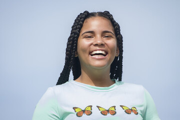 front portrait of one braided hair smiling young latin woman or girl looking to camera with a blue sky background