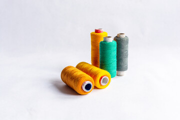 Five different yellow, red and gray colored sewing thread spools on isolated white background.