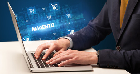 Fototapeta na wymiar Businessman working on laptop with MAGENTO inscription, online shopping concept
