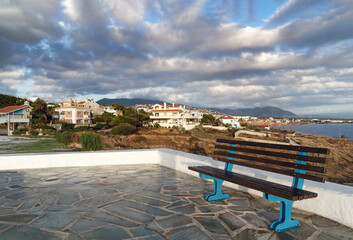 Fototapeta premium Relaxing place with a bench and view to Rafina city in Greece