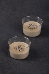 Vegan dessert Panna cotta cream sunflower paste with seeds in a glass Cup on a dark gray background
