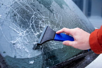 Ice crusted on car windows. Driver is scraping ice off the windshield. Freezing rain, anomalies of...