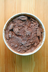 Cup of bitter sweet dark chocolate ice cream isolated on wooden background