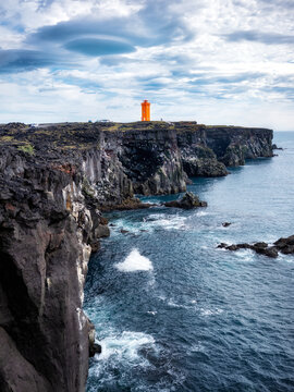 Lighthouse on rocks in Iceland. High rocks and lighthouse in day time. Natural landscape in summer. Iceland travel image