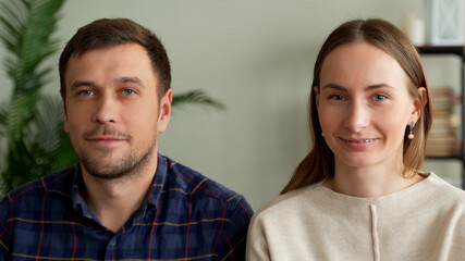 Portrait of a young couple sitting on a sofa. Couple looking at the camera