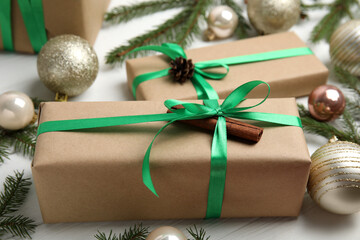 Fototapeta na wymiar Gift box with green ribbon and Christmas decor on white wooden table, closeup