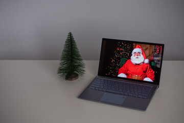 Santa Claus wishes Merry Christmas by video call on a laptop. Remote communication