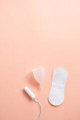 Menstrual hygiene products including tampon, menstrual cup and sanitary pad on peach background