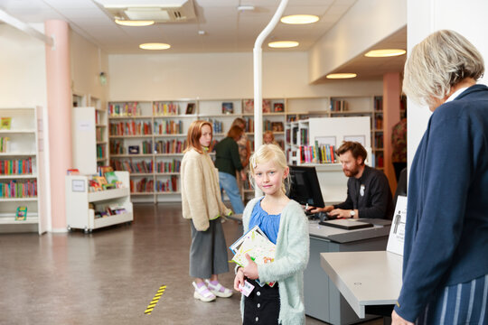 Girl holding books in library
