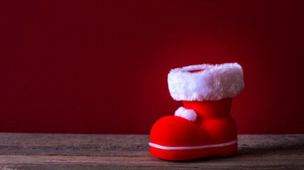 Ein roter Weihnachtsmannstiefel auf Holzbretter vor einem roten Hintergrund