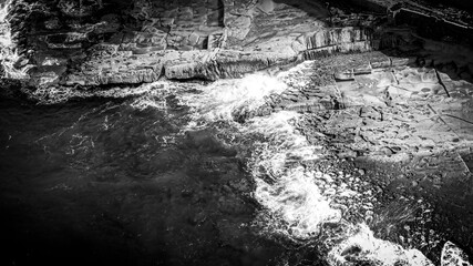 Wonderful turqouise blue ocean water hitting against the rocks - top down view - aerial photography