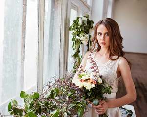 Beautiful bride in a wedding dress in a bright stylish Studio. Wedding in European style. Decor and bouquet in hand.