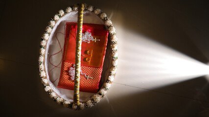 Folded traditional Kerala manthrakodi saree and red silk saree on a dish during Indian wedding