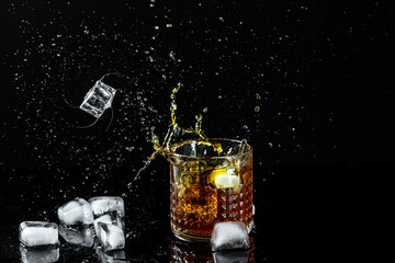 ice cubes fall into a glass with whiskey. Isolated shot of whiskey with splashes from falling ice fly in different directions. freeze motion