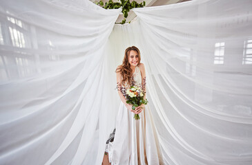 Beautiful bride in a wedding dress in a bright stylish Studio. Wedding in European style. Decor and bouquet in hand.