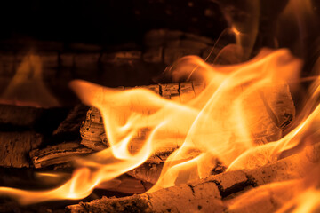 A blazing fire in the dark. Inflammation of firewood in the fire. A bright burning flames. Sparks and flames in the darkness. Red-hot heat and tongue flames.Fiery flaming bonfire.