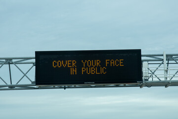 A highway message board reminds drivers to cover their face in public in the battle to defeat COVID-19