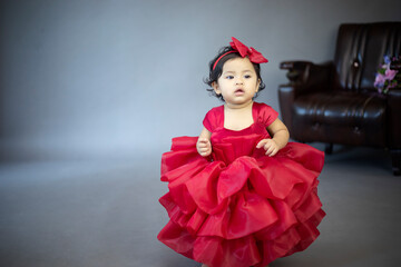 Lovely cute little Asian girl in a red dress is playing merrily and happily in her own home, promoting her skills and creativity..