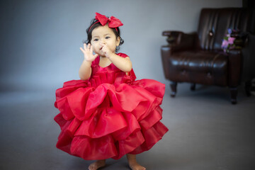 Lovely cute little Asian girl in a red dress is playing merrily and happily in her own home, promoting her skills and creativity..