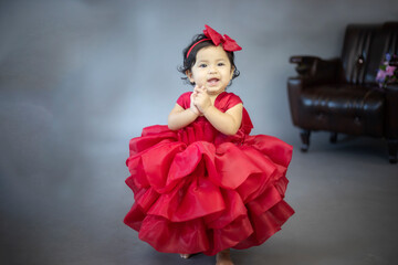 Lovely cute little Asian girl in a red dress is playing merrily and happily in her own home, promoting her skills and creativity..