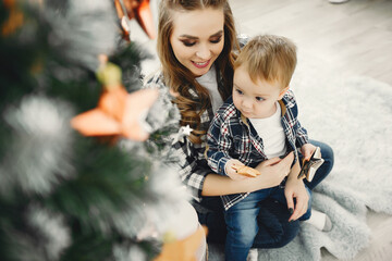 Beautiful family sitting near Christmas tree. Cute mother in a blue shirt