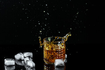 Isolated shot of whiskey with splash on black background.