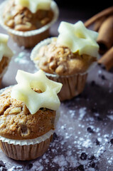 close up of delicious hand-made muffins decorated with a star-shaped pear, sugar and chocolate pear in festive atmosphere and colored lights.