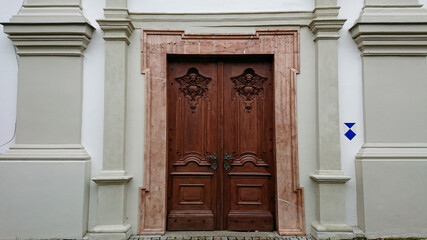 Old wooden doors of a Catholic Church with carved angels at the top