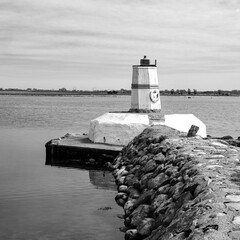 A lighthouse by a small fishing port, on the Swedish south coast in black and white