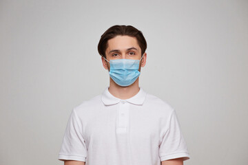 A man in a white T-shirt of European appearance in a medical mask. Covid 19 virus protection.