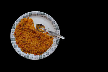 a top view of a plate of poha, a north indian dish spicy made of flattened rice chidwa with a spoon isolated in black background with space for text