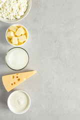 Set of healthy food most common dairy products are cheese, butter, milk, sour cream, cottage cheese top view on gray concrete background with copy space.
