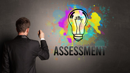 businessman drawing colorful light bulb with ASSESSMENT inscription on textured concrete wall, new business idea concept